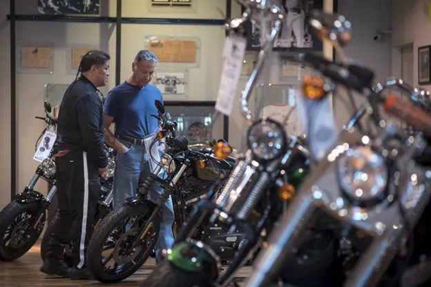 Image of a salesman talking to a man about options when buying a pre-owned motorcycle. Photo Credit: CNPC Autos