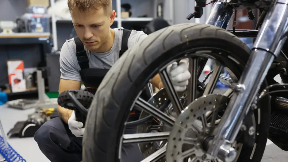 A mechanic checking the tire pressure of a motorcycle