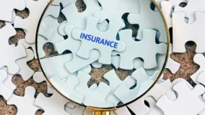 Image of white puzzle pieces with the word Insurance circled in a magnifying glass