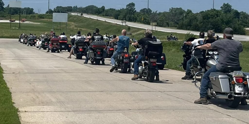 Bikers lined up on a road next to a highway for the 20th Annual Benjamin Smiles Toy Run