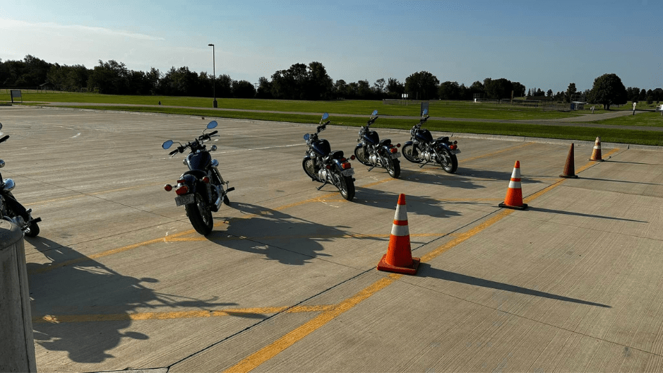 A row of five Yamaha Star 250 motorcycles is ligned up in a row in a parking lot at a Basic Rider Course