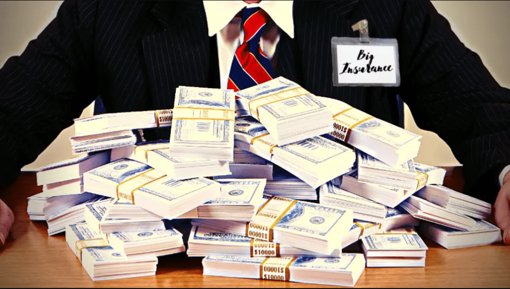 A man in a tie with a nametag that reads "Big Insurance" sits at a table with a big pile of american cash.