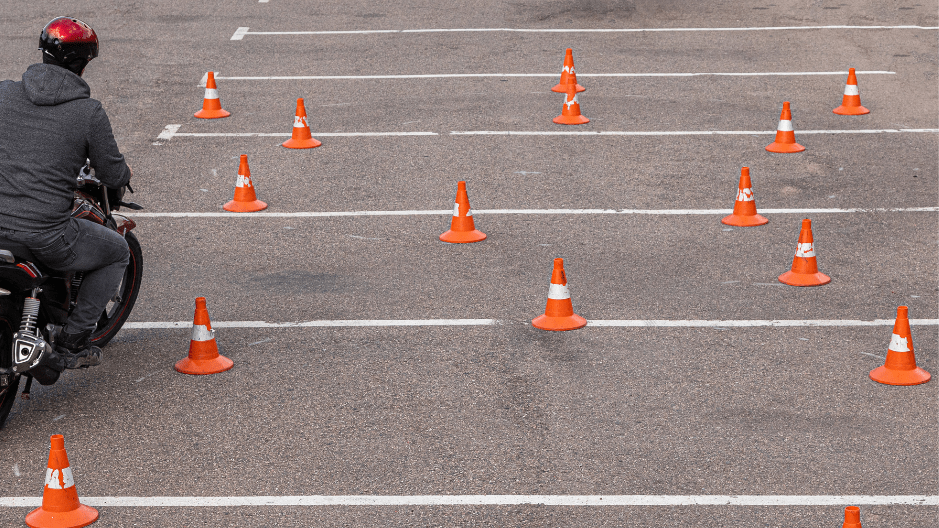 man on a motorcycle navigating cones on a closed course