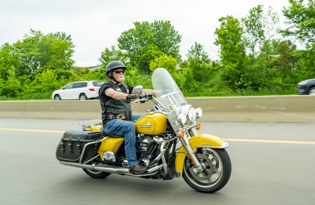 Minnesota Personal injury lawyer Dan Matzdorff rides his yellow harley davidson motorcycle on a highway