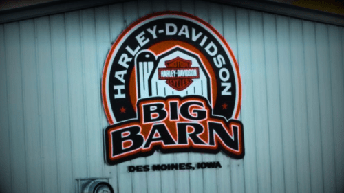 Big Barn Harley-Davidson dealership in Des Moines, Iowa, featuring the iconic orange and black Harley-Davidson logo on the building.