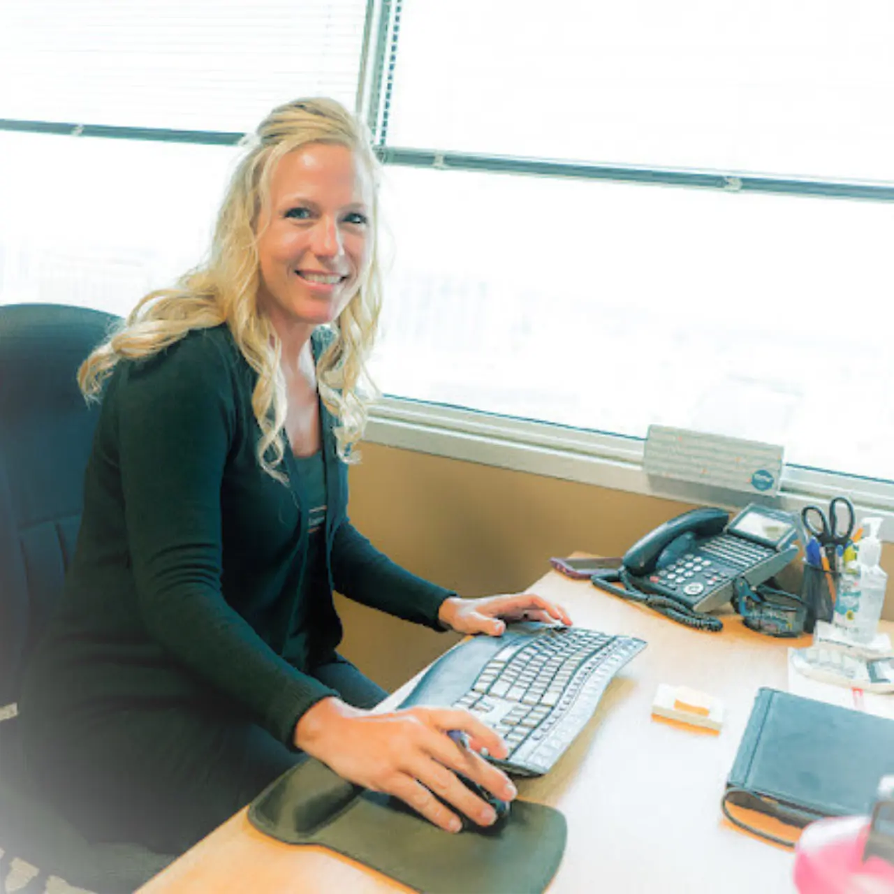 Jen, Paralegal with The Biker Lawyers Personal Injury law firm, sits at her desk helping research a case to prepare for trial. She has long blonde hair and wears a black sweater