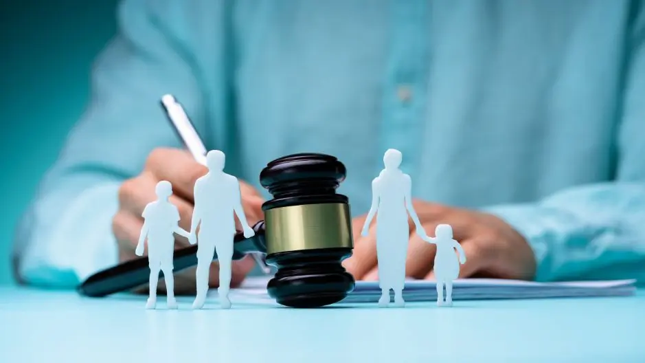 A lawyer sits behind a gavel with paper cutouts of a family representing family law