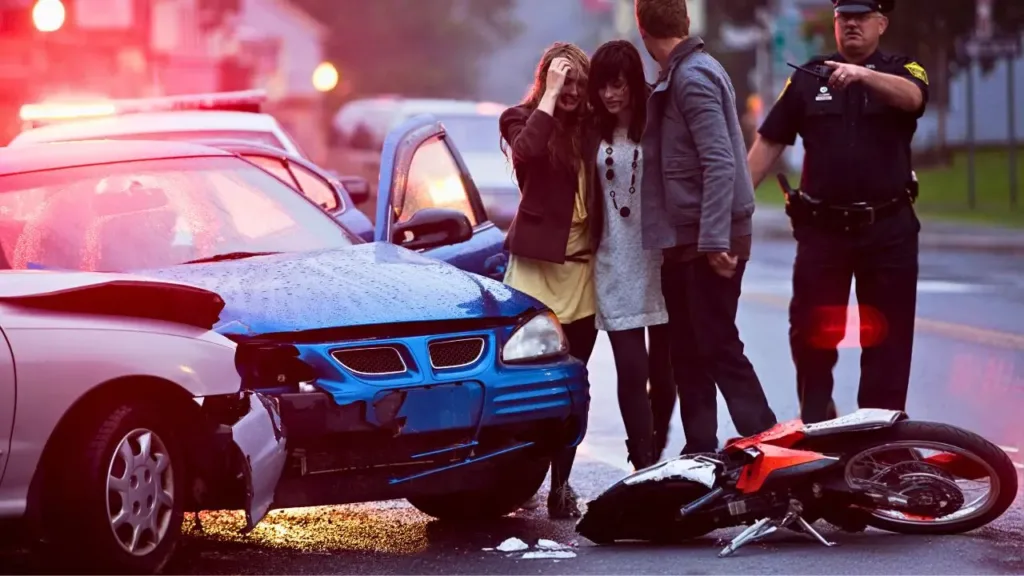 The scene of a multi-car accident with two cars, a motorcycle, three injured people and a police officer