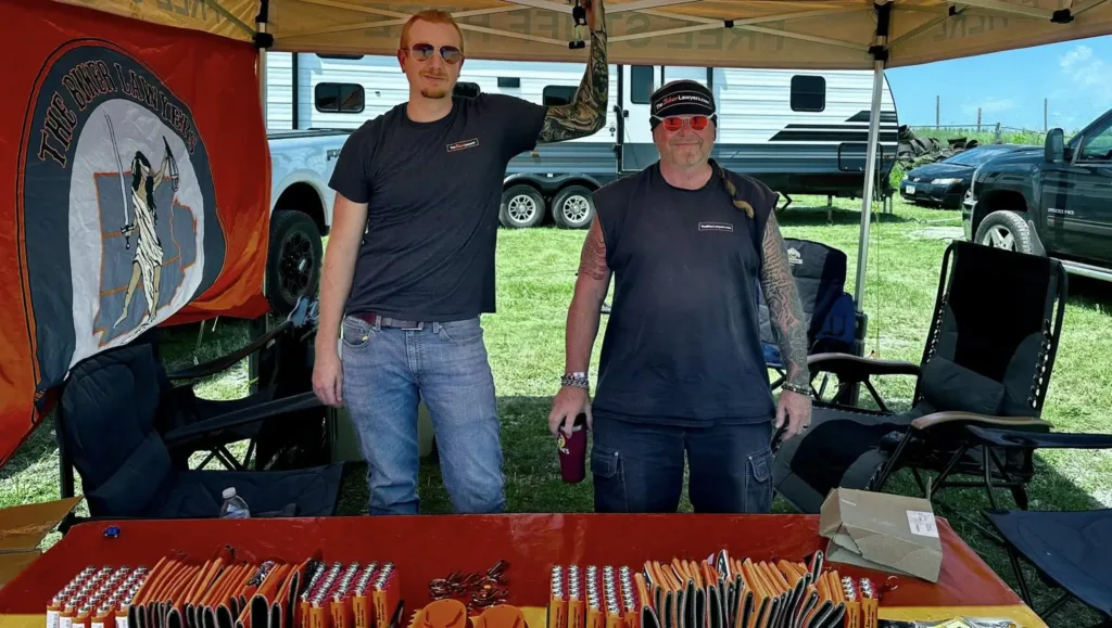 Image of Biker Lawyers Jon Jansen and Pete Leehey at a Biker Rally free merch table