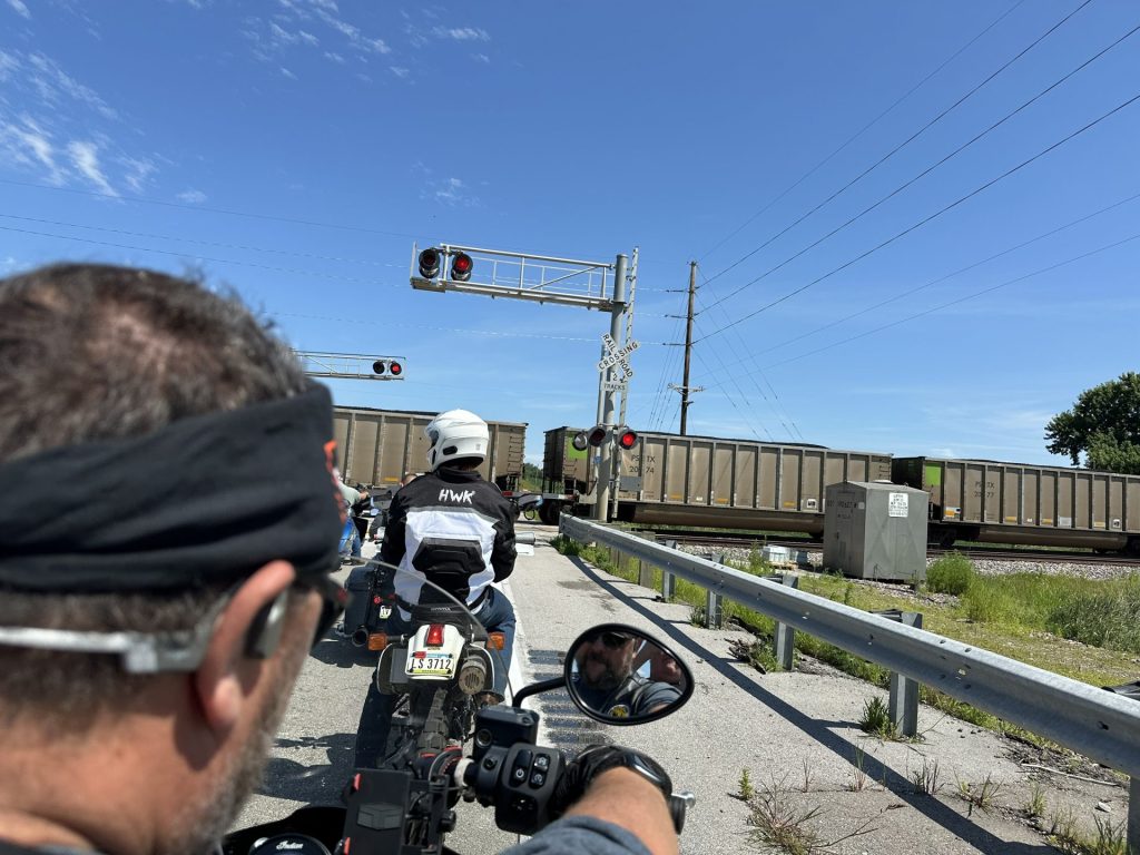 Over-the-shoulder photo of a motorcycle rider on a group ride that has been split up due to a train in the path